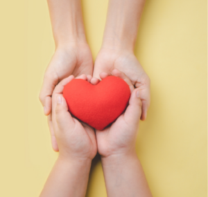 hands holding a red toy heart